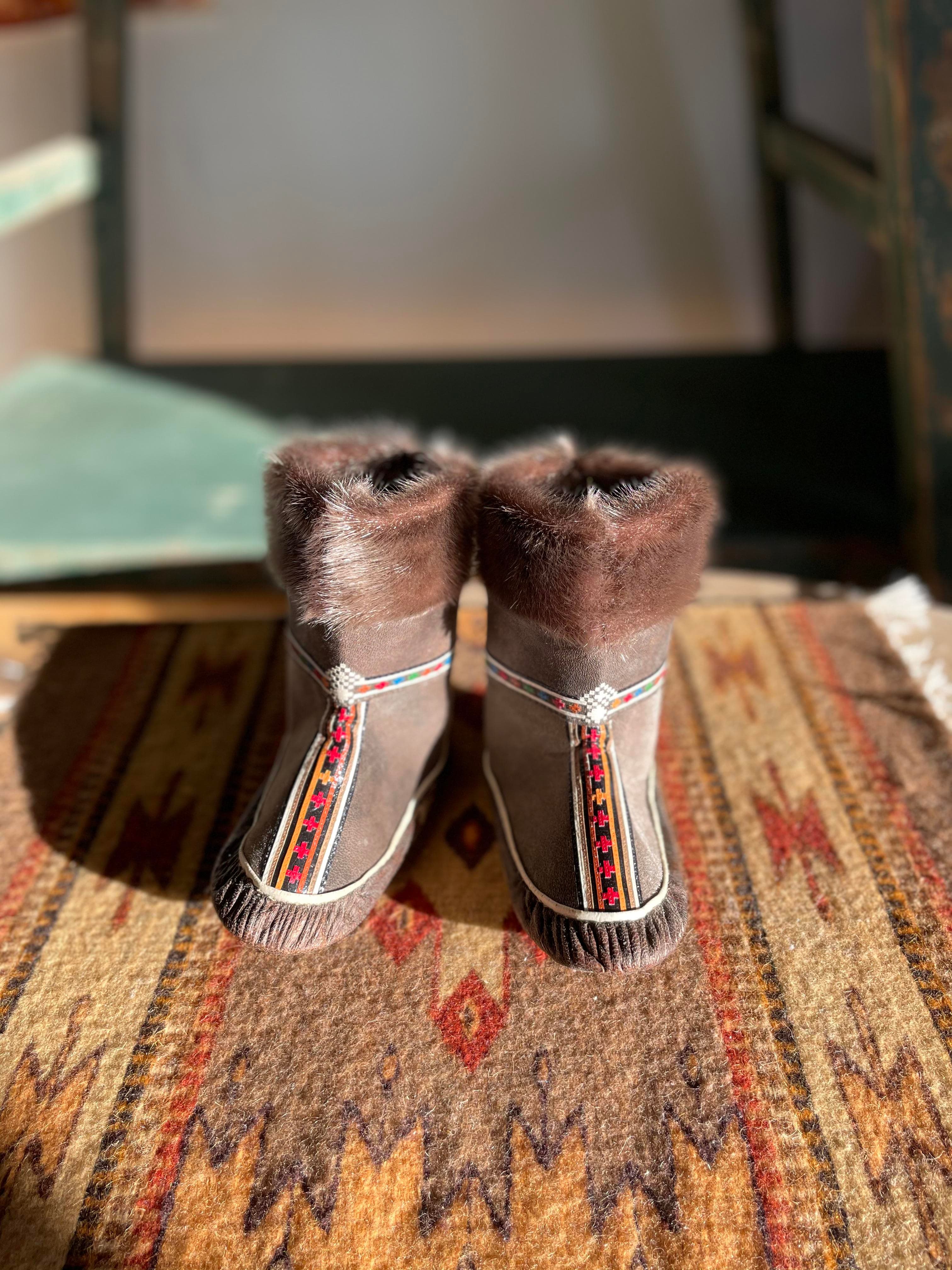 A pair of handmade fur boots with colorful decorative trim