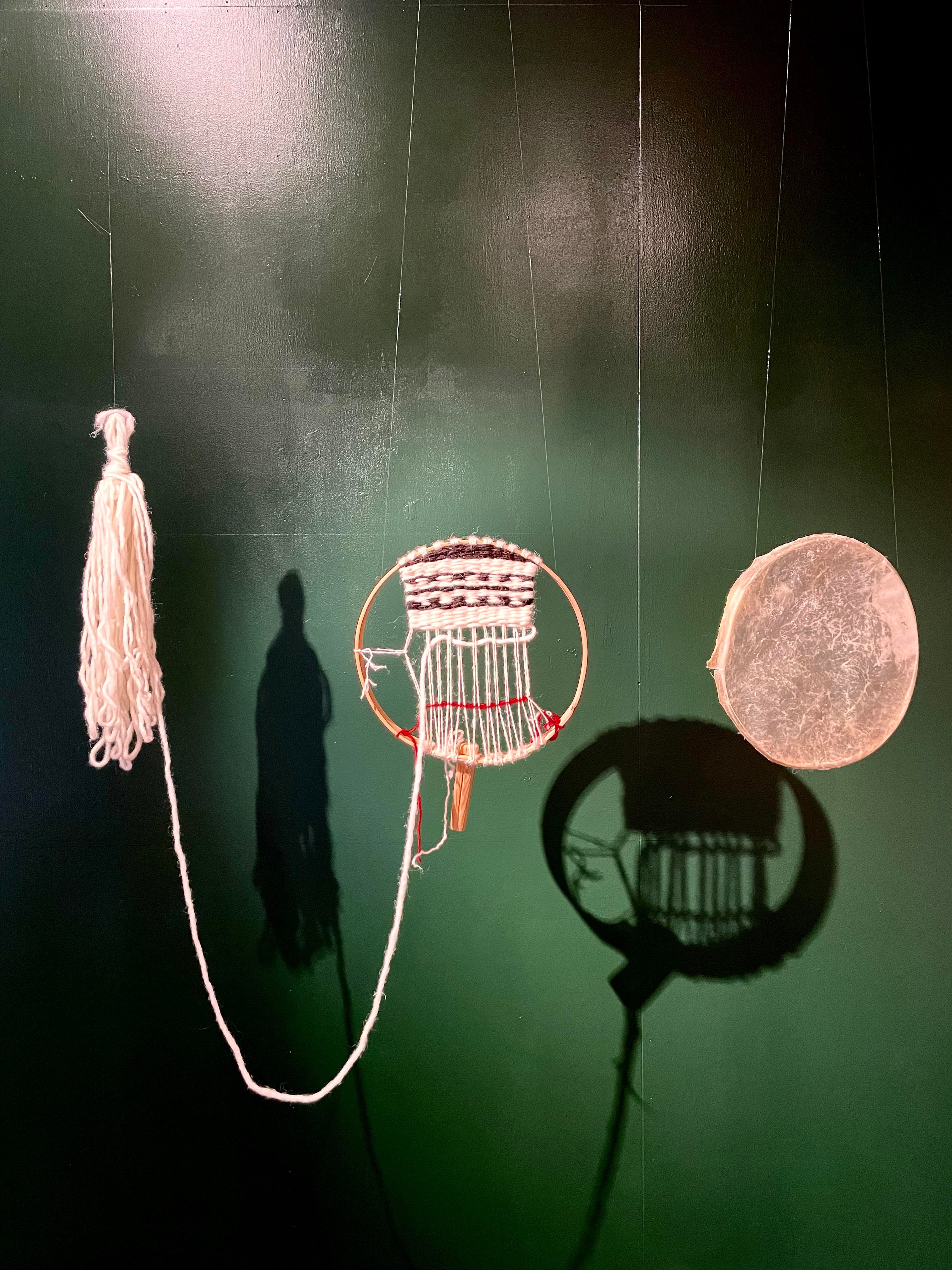 A textile installation suspended against a deep green wall